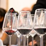 Banco di degustazione del Primitivo di Manduria con calici e sommelier durante un evento vino